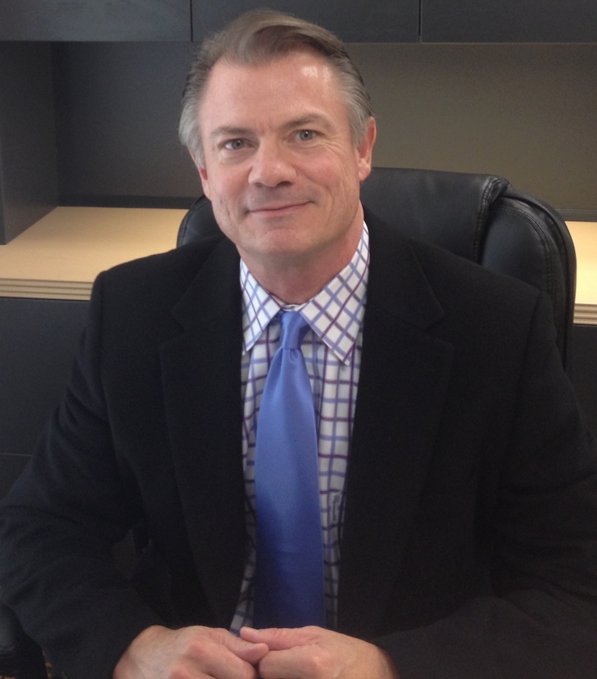 A man in a suit and tie sitting at his desk.